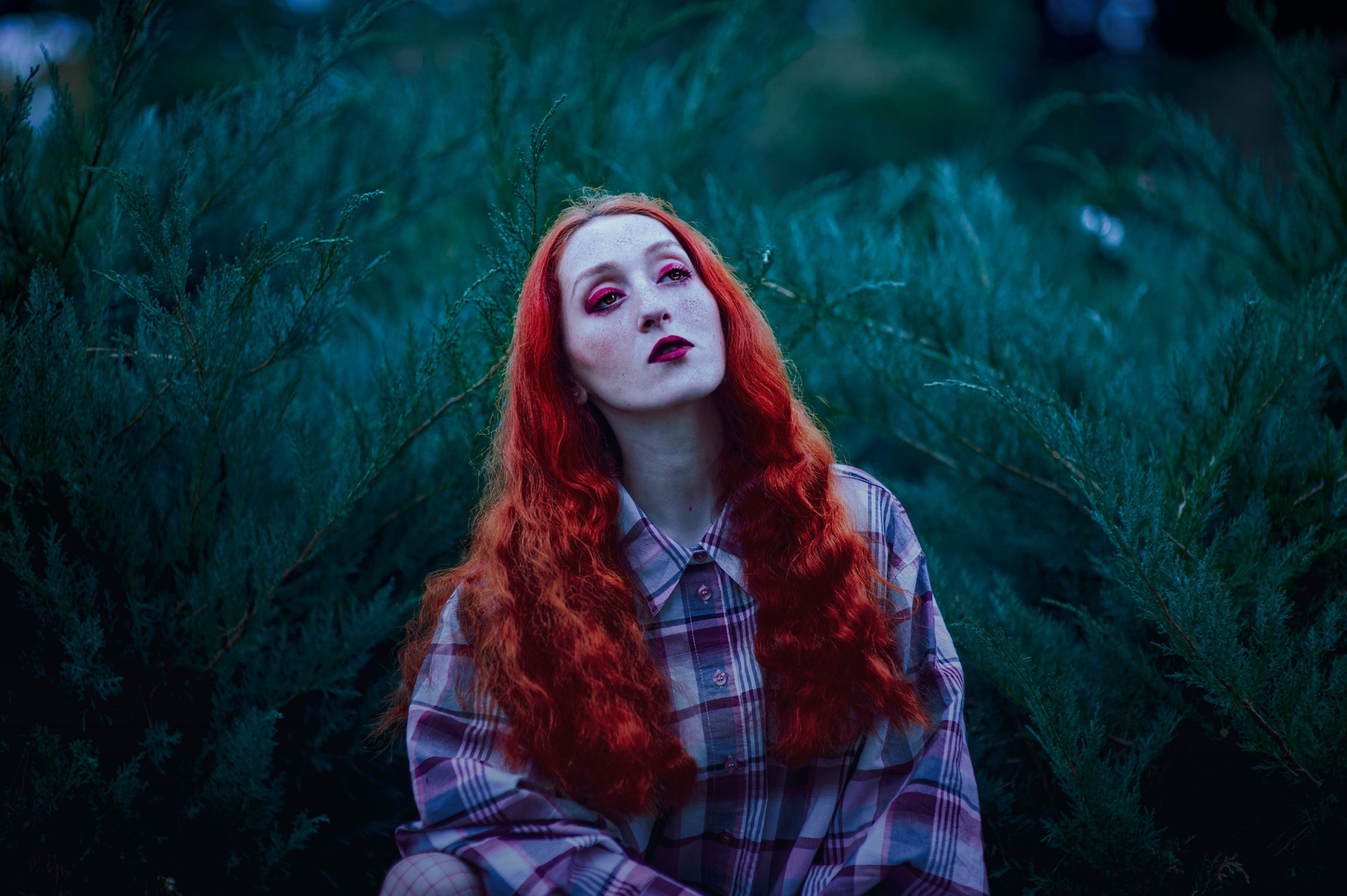 woman with red hair and red lipstick near green leafed plants